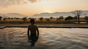 A person standing in a swimming pool with a view of mountains and trees in the background. - Tandweni Villa (Pongola)