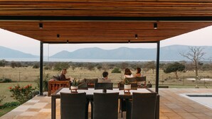 An outdoor patio with a table and chairs, overlooking a scenic landscape with mountains and a body of water. - Tandweni Villa (Pongola)
