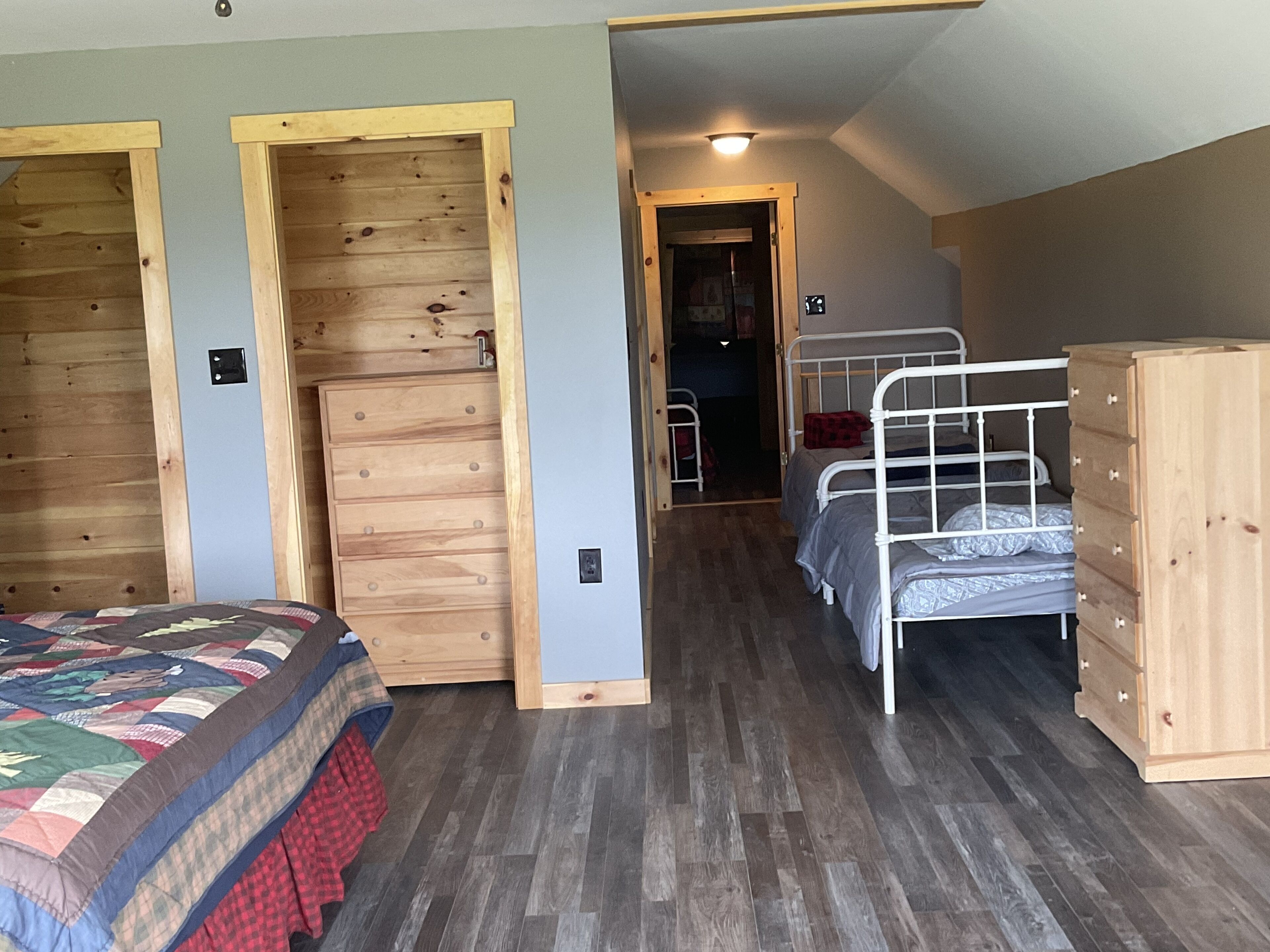 A bedroom with a wooden wardrobe, a bed with a quilt, and a bunk bed.