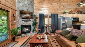 Un salon chaleureux avec une cheminée en pierre, un plafond en bois et un canapé en cuir.