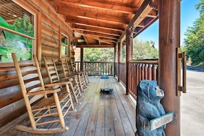 A wooden porch with rocking chairs and a welcome sign.