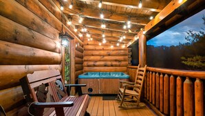 L’intérieur d’un chalet en bois, avec un jacuzzi, une terrasse en bois et une vue sur la forêt.