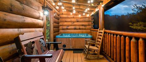 A wooden cabin interior with a hot tub, wooden deck, and a view of the forest.
