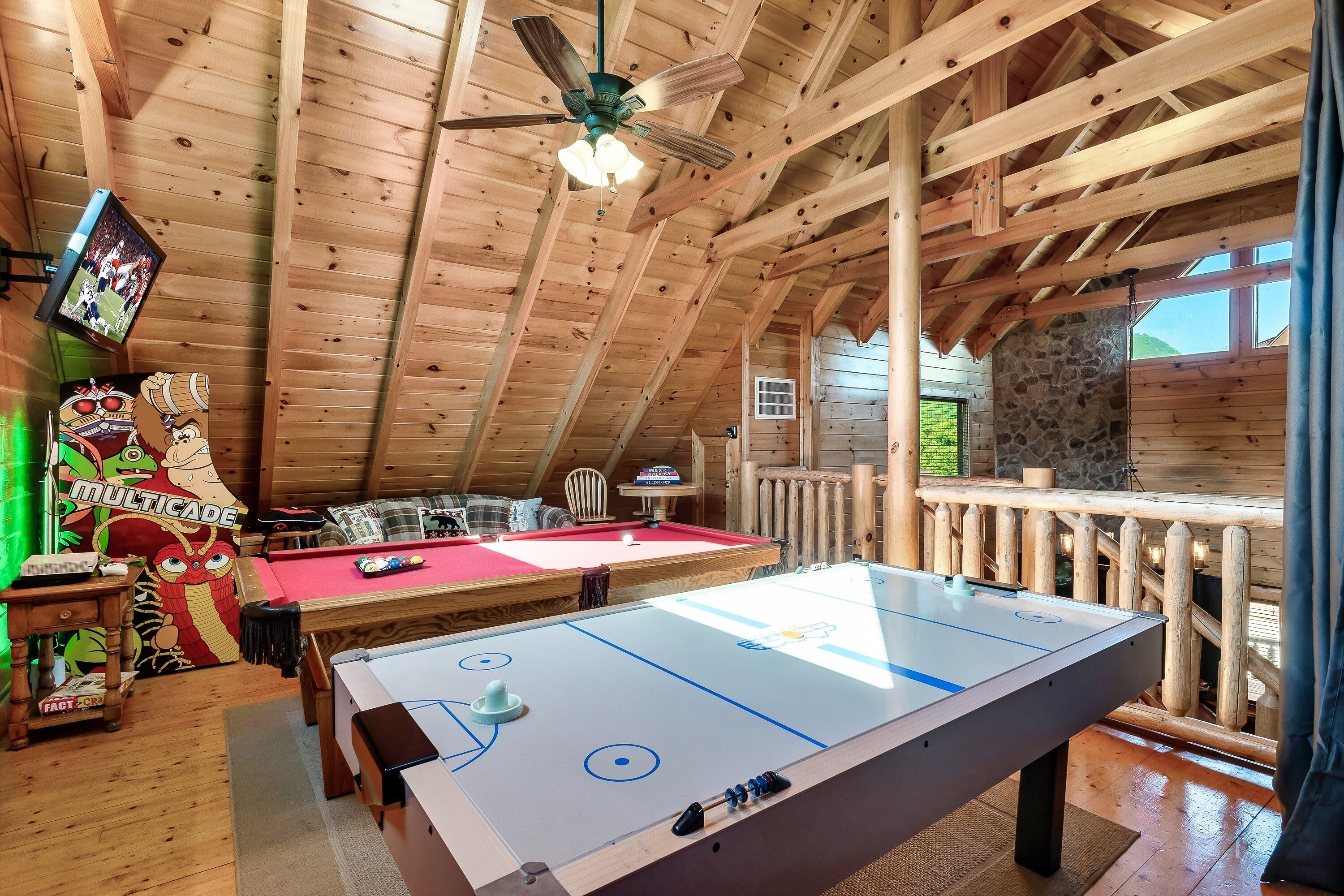 Un intérieur en bois avec une table de billard, un baby-foot et un ventilateur de plafond.