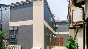 Um edifício moderno com telhado plano, janelas amplas e entrada protegida por grades.