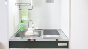 Uma cozinha compacta com pia, torneira e fogão de indução embutido.