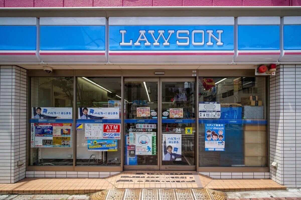 Ein Lawson Geschäft mit einer blau und weißen Fassade, Glastüren und verschiedenen Werbeplakaten.