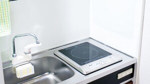 A compact kitchen with a built-in induction cooktop and a stainless steel sink.