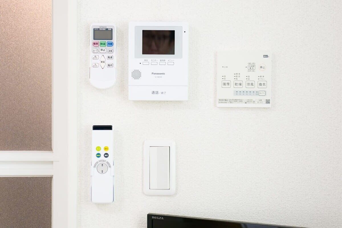 A wall-mounted control panel with a remote, a security camera, and a thermostat.