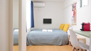 Une chambre à coucher avec un lit, un bureau, une chaise et un téléviseur.