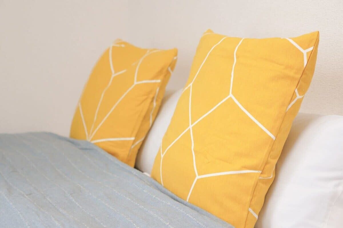 A bed with two pillows and a blue blanket.