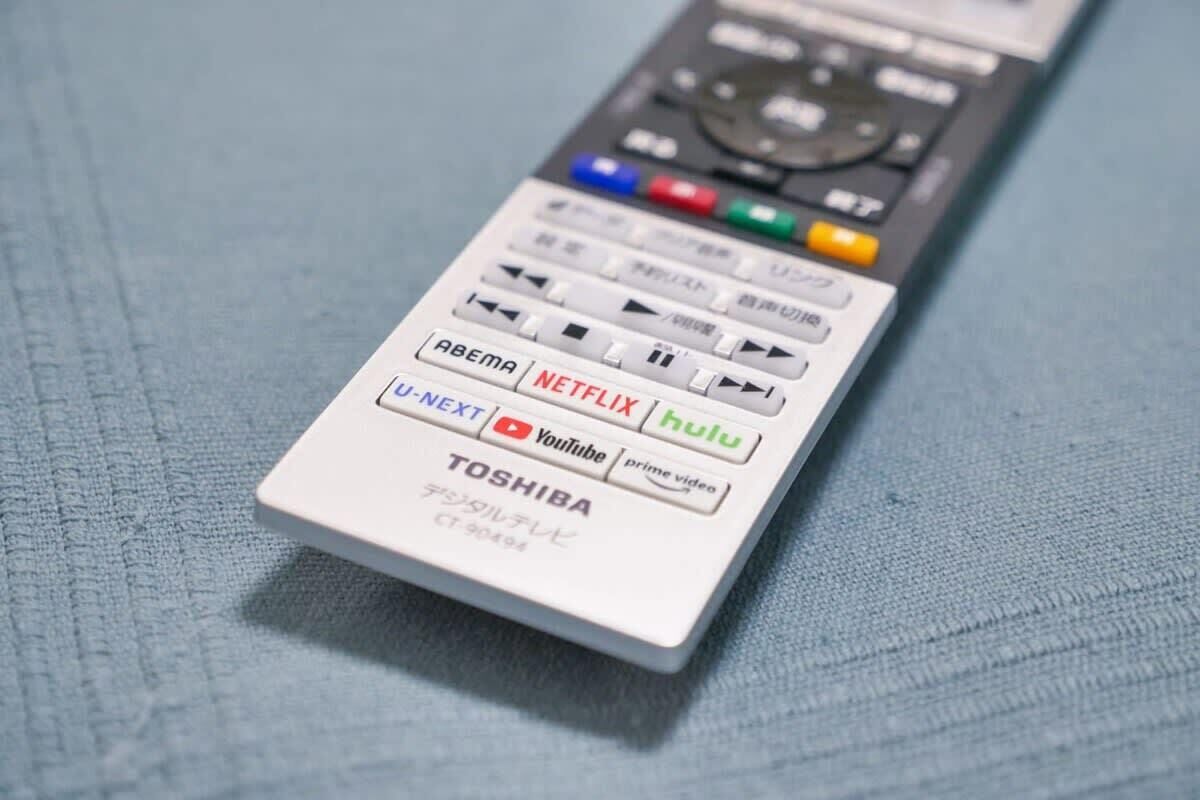A remote control with various buttons and logos, including U-NEXT, Netflix, and Hulu.