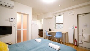 A hotel room with a bed, a desk, two chairs, a television, and a kitchenette. - Triphome 101/big table/Free WiFi/Asakusa SkyTree (Katsushika City)