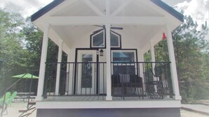 A covered outdoor area with a white roof, black railings, and a bench.