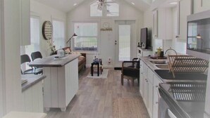A spacious kitchen with a central island, a dining area, and a large window providing natural light.