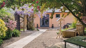 A garden pathway leading to a wooden structure with a pergola covered in purple flowers. - 2 bedroom accommodation in Ulrome (Ulrome)