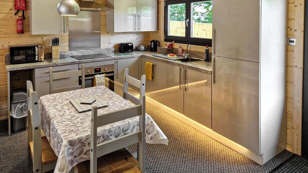 A compact kitchen with wooden walls, a stainless steel refrigerator, a microwave, and a sink. - 2 bedroom accommodation in Ulrome (Ulrome)