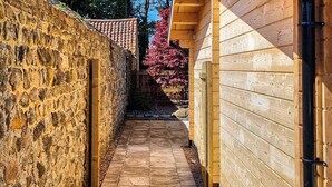 A narrow stone pathway leading to a wooden building with a tiled roof. - 2 bedroom accommodation in Ulrome (Ulrome)