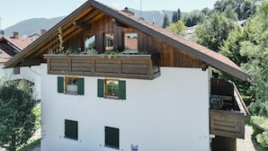 Una casa de dos pisos con un balcón de madera y fachada blanca.