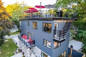 A multi-level house with a balcony, outdoor seating, and a staircase. - Rooftop patio Hot Tub/ 2 BBQ/ firepit/Full Games room/7 Beds/5 floors (Grand Bend)