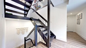 Um interior moderno com escada de madeira, paredes brancas e piso de madeira.