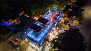 Vista aérea de um edifício com terraço no telhado, painéis solares e área de estar externa.