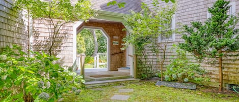 Stroll through the beautifully maintained garden, featuring a variety of plants and a stone pathway leading to the traditional home's covered entrance.