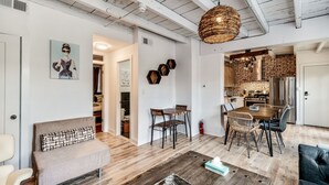 A spacious living area with a high ceiling, a dining table, and a kitchen visible through an open doorway.