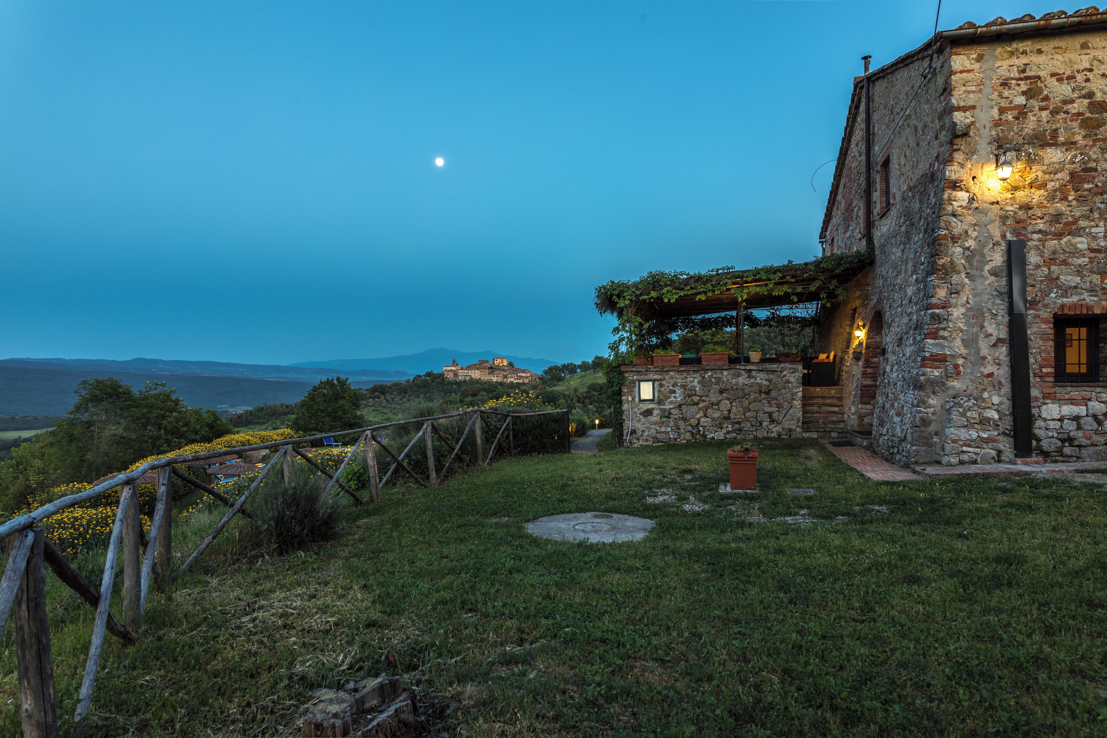 A stone building with a garden and a view of the mountains.