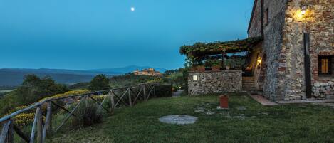 A stone building with a garden and a view of the mountains.