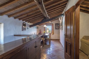 A rustic kitchen with exposed wooden beams, a large wooden counter, and a view through a window to the outside. - Country Cottage (B) with pool - Le Caldanelle (Civitella Paganico)