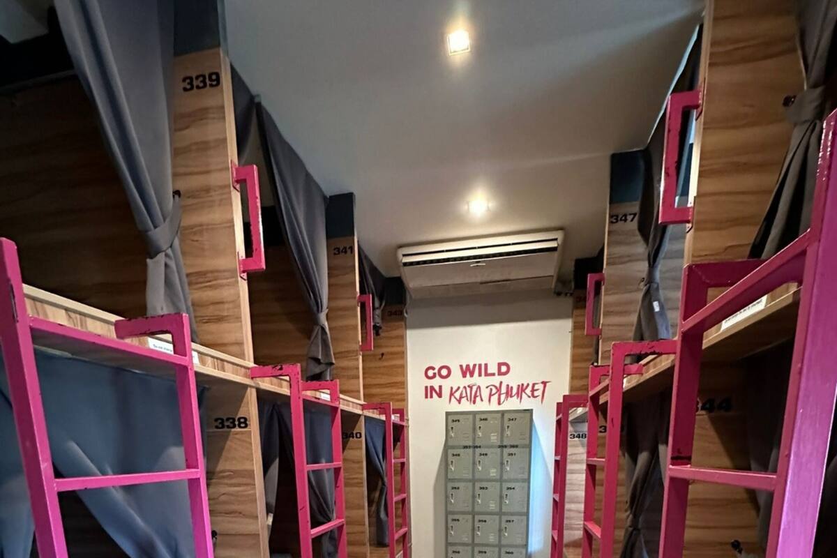 A corridor with bunk beds and a sign that reads "GO WILD IN KATA PHILKET".