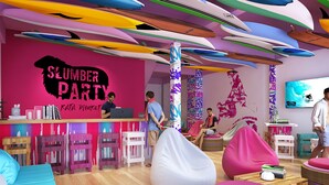Een levendig interieur met een 'Slumber Party'-thema, met kleurrijke decoraties aan het plafond, een bar en speelse zithoeken.