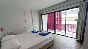 Een hotelkamer met een bed, een raam met uitzicht op een balkon, en een deur naar het balkon.