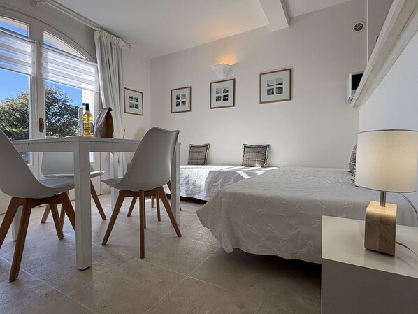 Une chambre à coucher avec un lit, une table de chevet, une lampe et une fenêtre avec des rideaux.