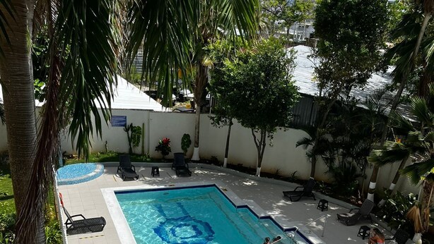 A swimming pool with a tiled deck, surrounded by palm trees and lounge chairs. - Stunning 3 Bedrooms Apartment in San Andres (San Andrés)