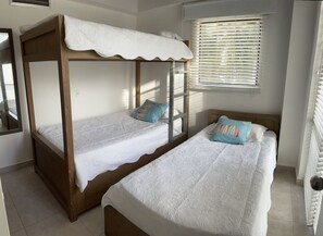 Ein Schlafzimmer mit zwei Betten, eines mit Baldachin und eines ohne, beide mit weißer Bettwäsche und gemusterten Kissen.