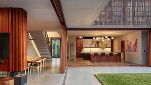 Un interior moderno con comedor, cocina y una escalera que sube a un nivel superior.