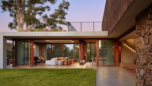 Una casa moderna con un salón espacioso, ventanas amplias y una pared de piedra.
