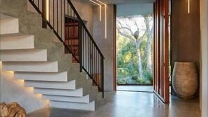 Una escalera moderna de diseño minimalista que lleva a una habitación con un amplio ventanal con vistas al verdor.