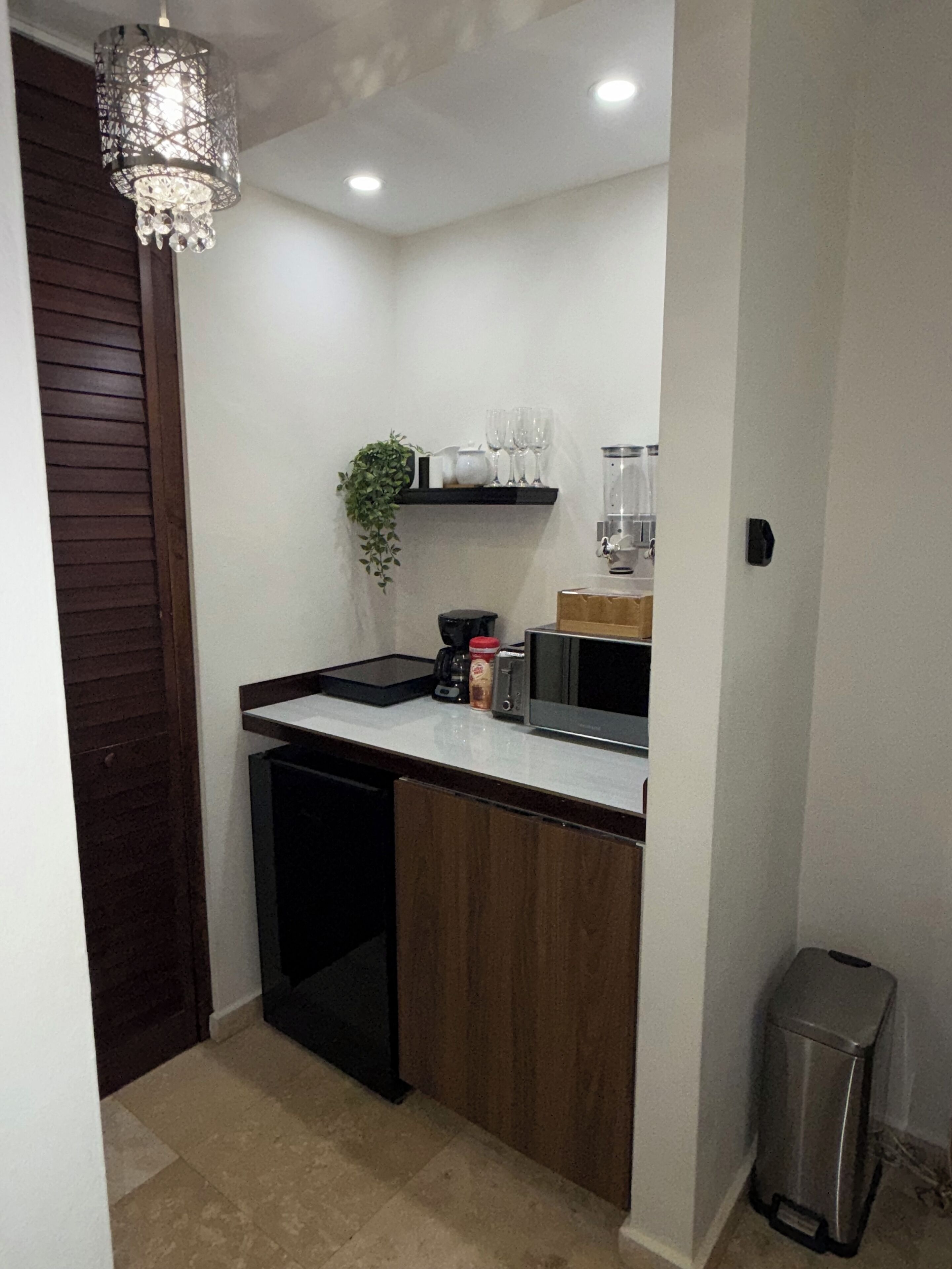 Una cocina compacta equipada con microondas, cafetera y un cubo de basura.