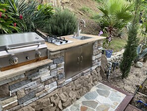 An outdoor kitchen with a gas stove, sink, and stone counter. - "Garden" Suite near the beach and restaurants! (Ucares)