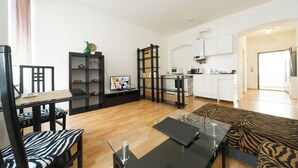 Ett modernt vardagsrum med en TV, en svartvit mönstrad soffa och ett soffbord i glas.