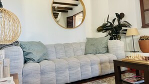 A living room with a light grey sofa, a round mirror, a potted plant, a lamp, and a chessboard. - Amazing villa, superb views, close to village, private pool (Canillas de Aceituno)