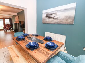 Un comedor con una mesa de madera dispuesta para seis personas, platos azules y un vaso transparente.