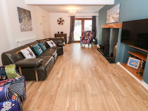 Una sala de estar con sofá, sillones, chimenea y televisión.