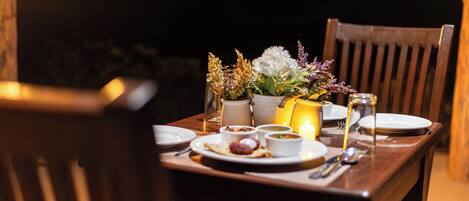 A dining table set for two with plates, bowls, and a candle.