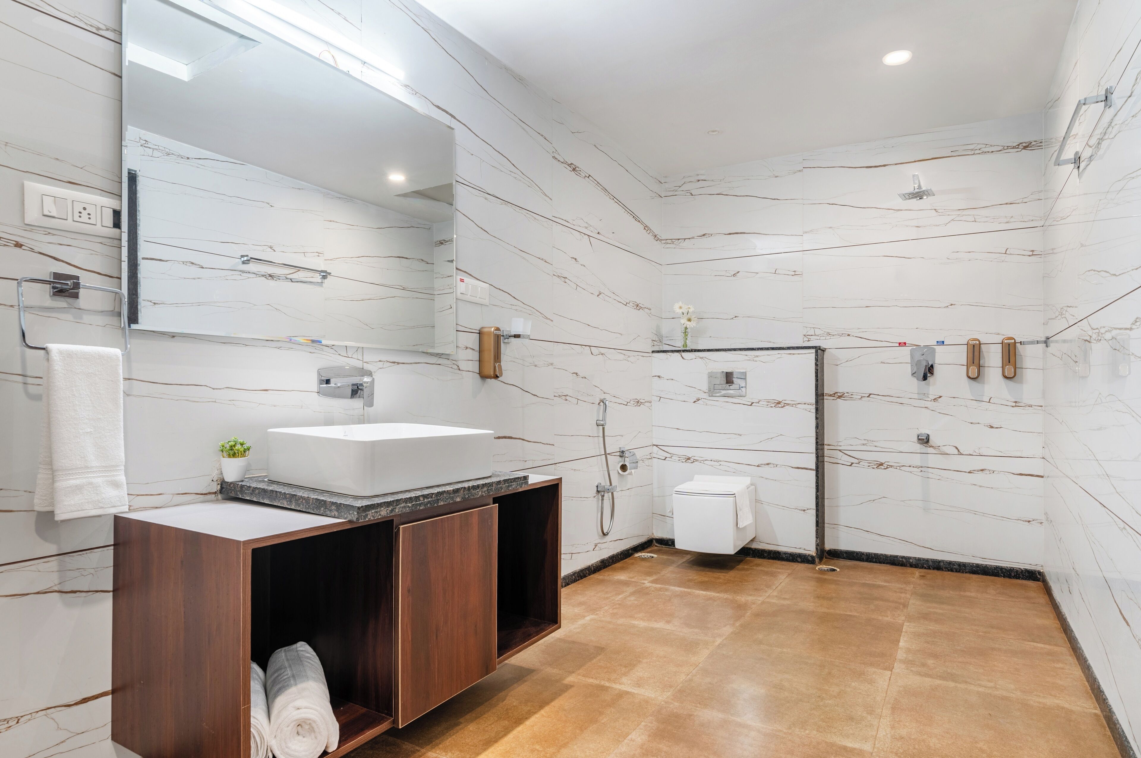 Un baño moderno con salpicadero de mármol, un espejo grande, un tocador de madera, una ducha y un inodoro.
