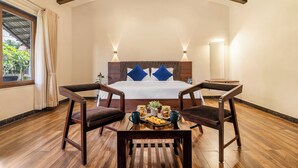A bedroom with a bed, two chairs, a table with breakfast, and a window with curtains. - Sterling Banashree Badami  (Badami)