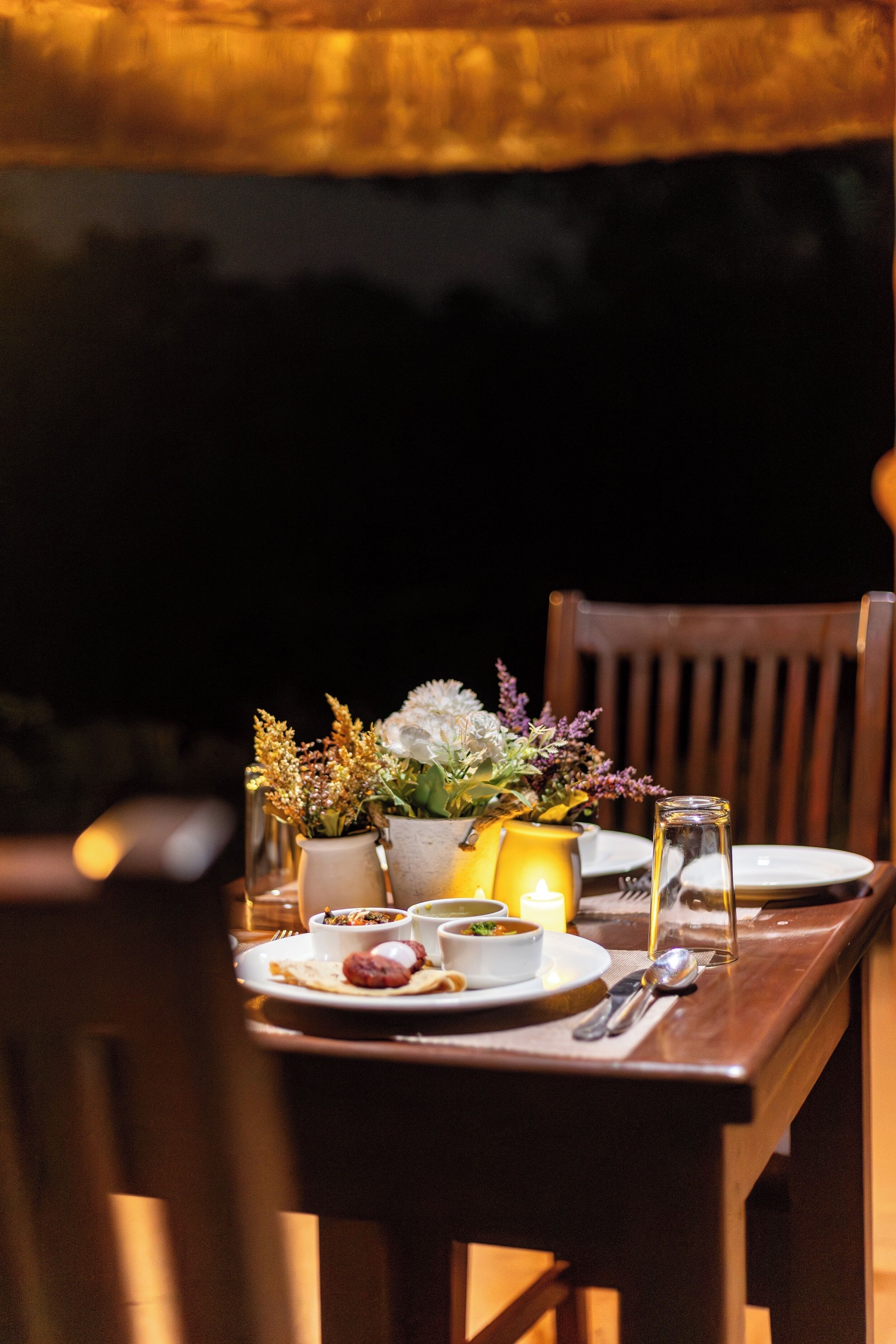 A dining table set with plates, bowls, cutlery, and candles.